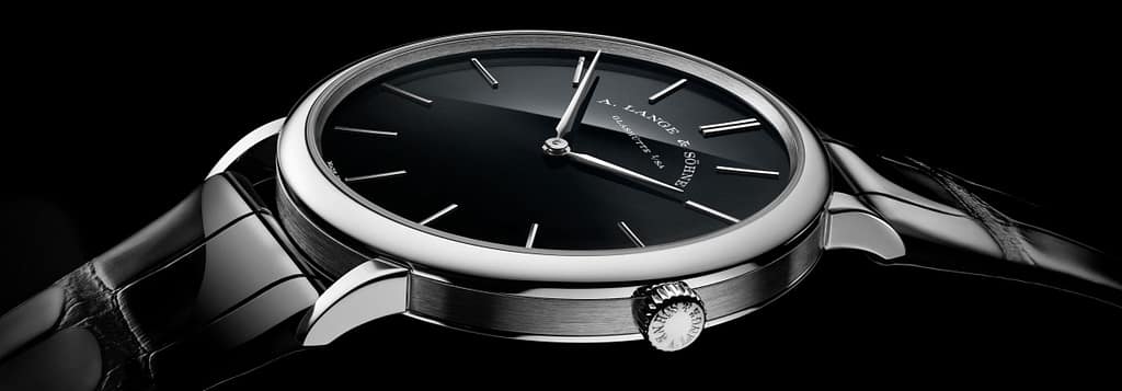 Close-up view of an A. Lange & Söhne Saxonia Thin watch featuring a jet-black onyx dial, silver case, and a glossy black alligator strap.