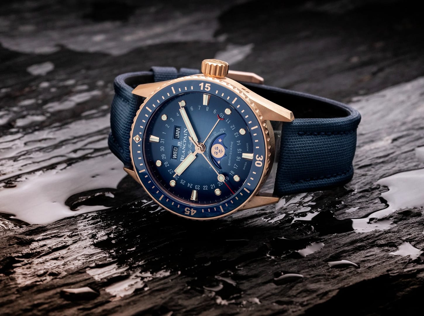 Blancpain Fifty Fathoms dive watch with a calendar and moon phase in red gold with blue dial on a blue fabric strap.
