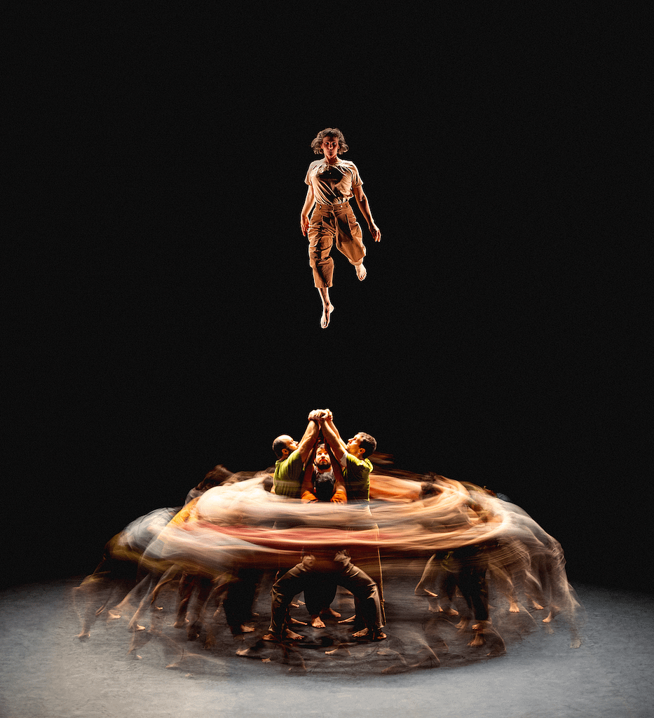 A dancer jumping onstage in the air above three others during Van Cleef & Arpels Dance Reflections series.